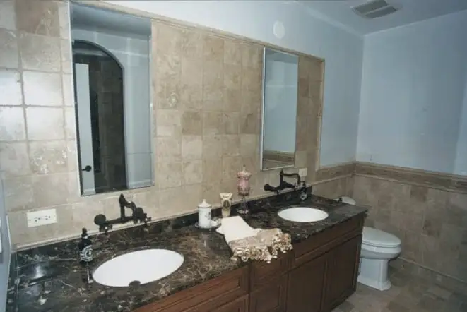 Dark granite double vanity in a beige tiled bathroom