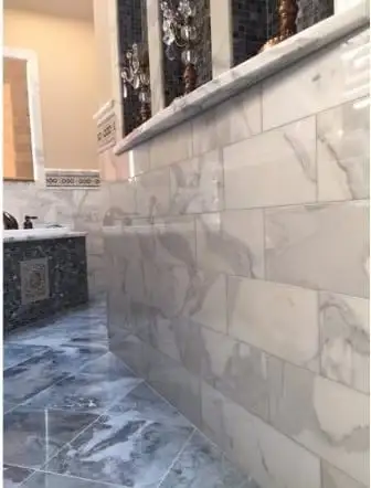 Grey marble tile wrapping a tub and shower area