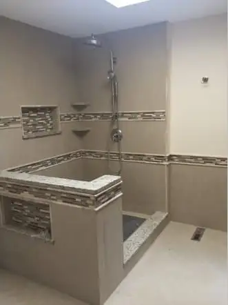 Curbed shower with a granite threshold and mosaic accent tile