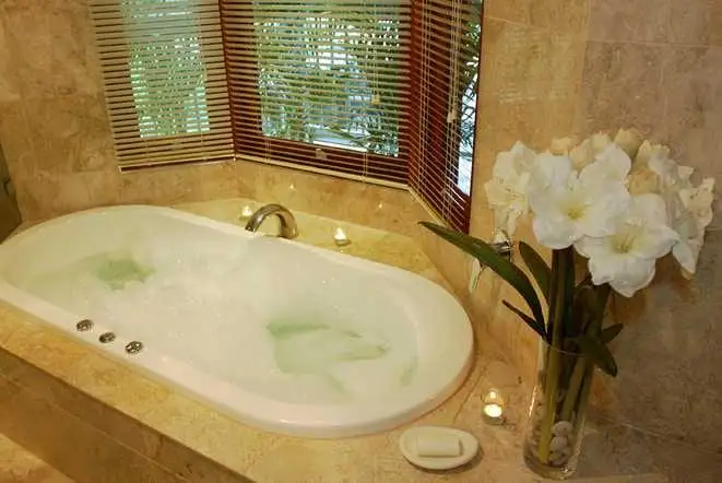 Drop-in tub set into a stone surround below a bay window