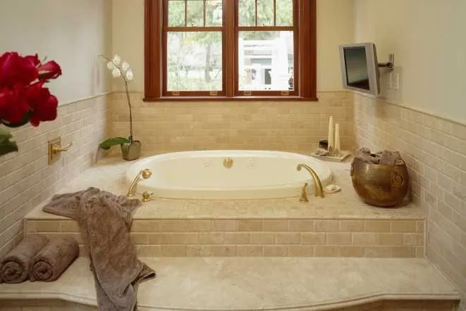 Soaking tub with a tiled surround and dark wood window trim