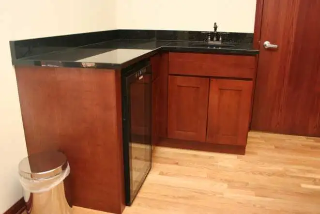 Office bar and kitchenette with a black granite top on cherry cabinets