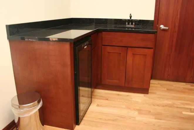 Office bar and kitchenette with a black granite top on cherry cabinets