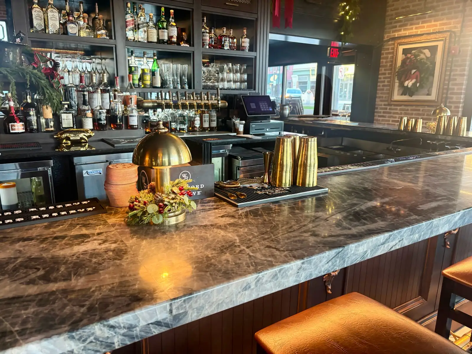 Restaurant bar topped in dramatic grey quartzite with brass barware and a back-bar of spirits