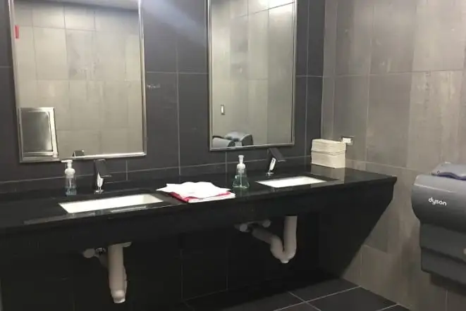 Commercial restroom with a long dark granite vanity and twin sinks