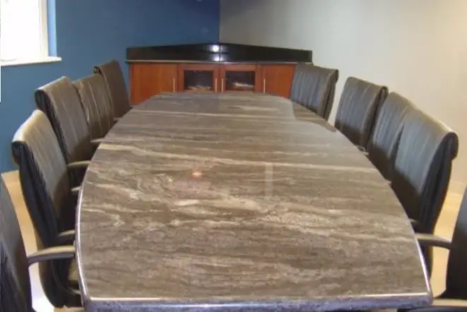 Long conference table topped in travertine-toned stone