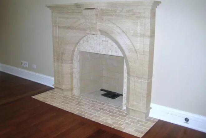 Arched limestone fireplace surround with a raised stone hearth
