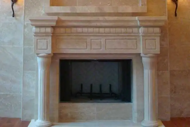 Cast stone fireplace mantel with fluted columns and a raised hearth