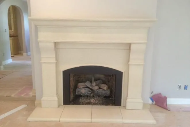 Cream cast stone fireplace mantel with a tiled hearth