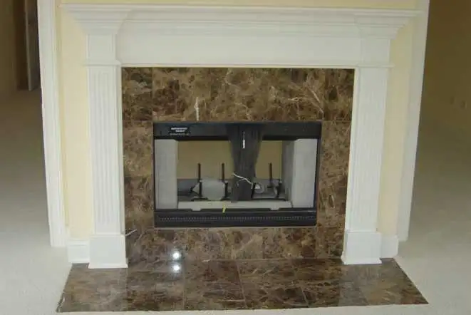 Dark marble fireplace surround and hearth under a white painted mantel