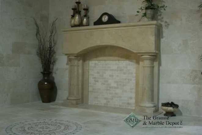Limestone fireplace mantel with columns above a mosaic tile surround