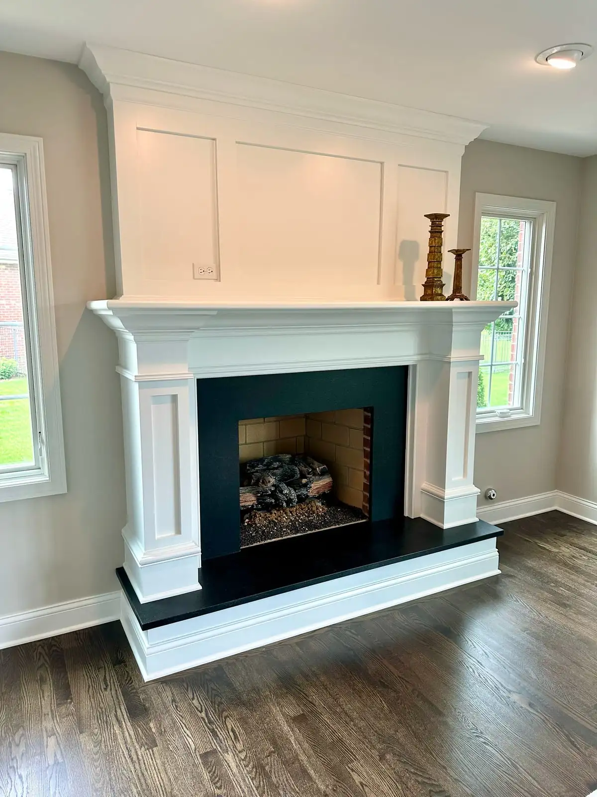 White paneled fireplace mantel with an absolute black granite surround and hearth