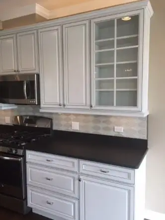White cabinets with black stone countertops and glass-front upper doors