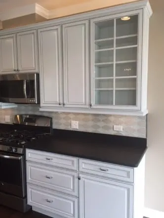 White cabinets with black stone countertops and glass-front upper doors