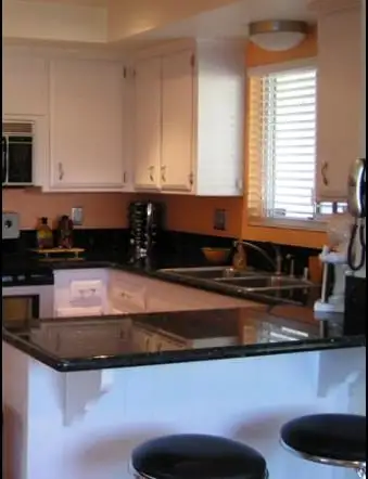 Black granite peninsula with bar stools and white cabinetry