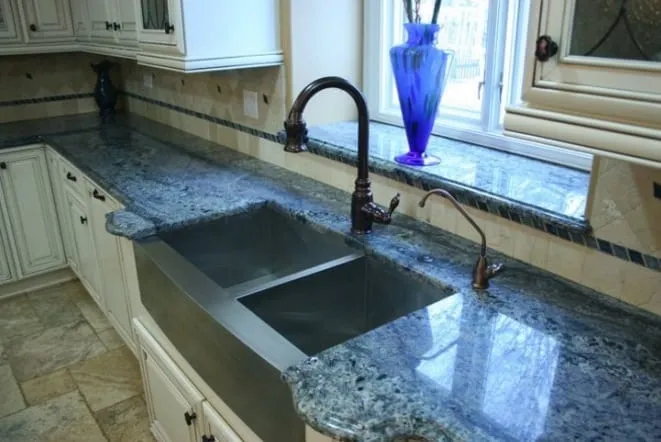 Blue-green granite countertop with a large undermount sink below a garden window