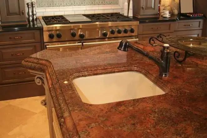 Warm brown granite countertop with a drop-in cooktop and undermount sink