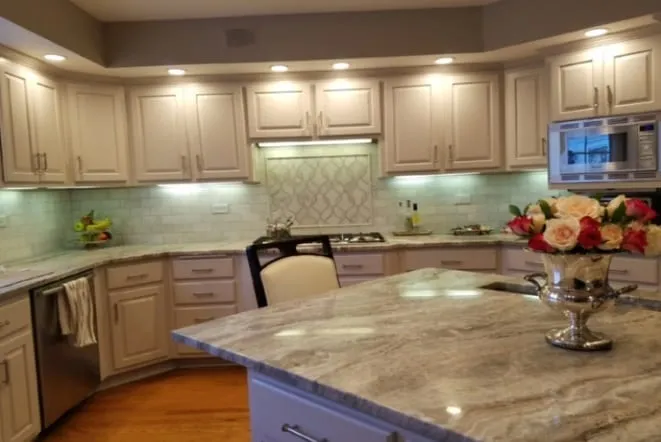 Cream cabinets with brown granite countertops and an arched window