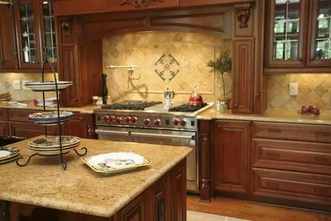 Honey-toned cabinets and cream granite counters with a decorative tile medallion above the range