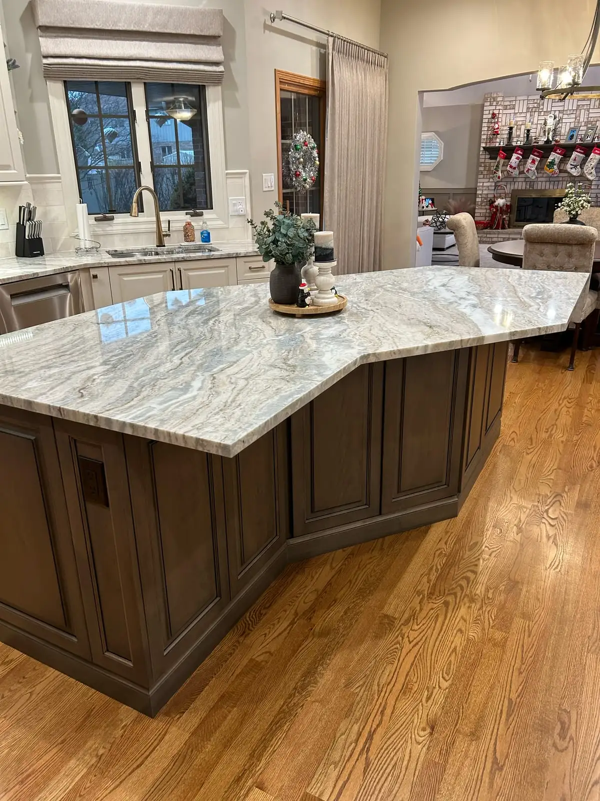 Angled kitchen island topped in fantasy brown granite with warm wood cabinetry