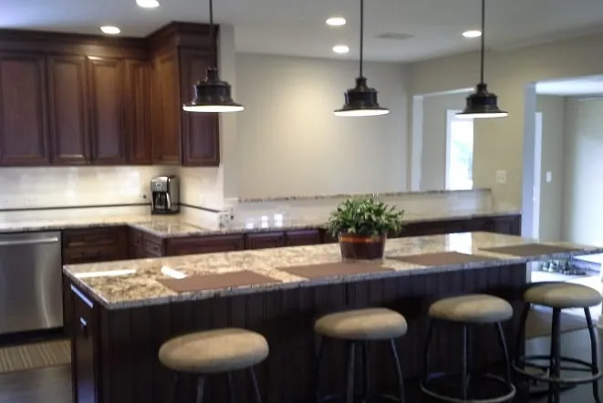 Gold granite bar counter with upholstered stools in a dark-cabinet kitchen