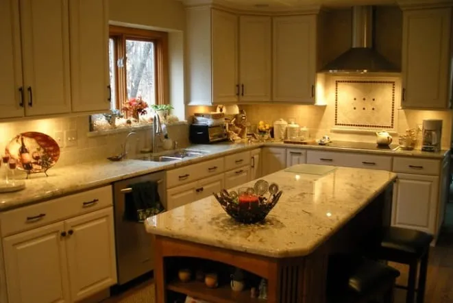 Cream cabinets with gold granite counters and a matching island