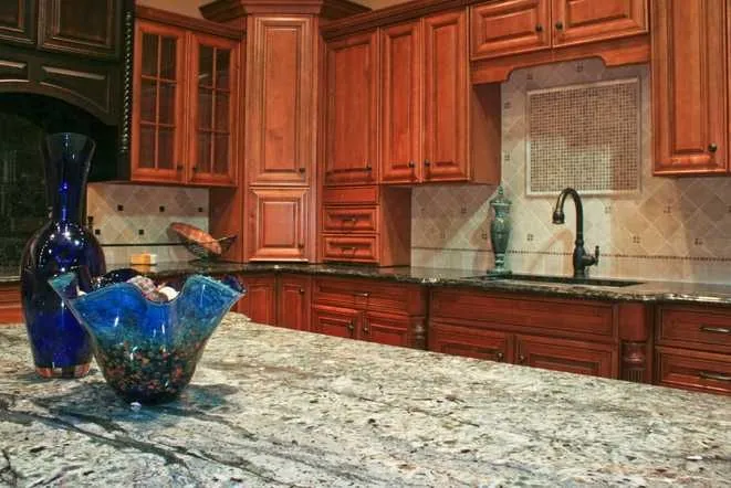 Cherry cabinets with light granite perimeter countertops and an undermount kitchen sink