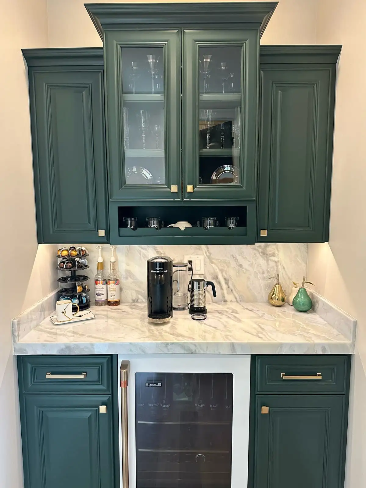 Beverage station with deep green cabinets, a marble-look counter and matching slab backsplash
