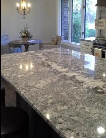 Grey granite island with a breakfast area and windows beyond