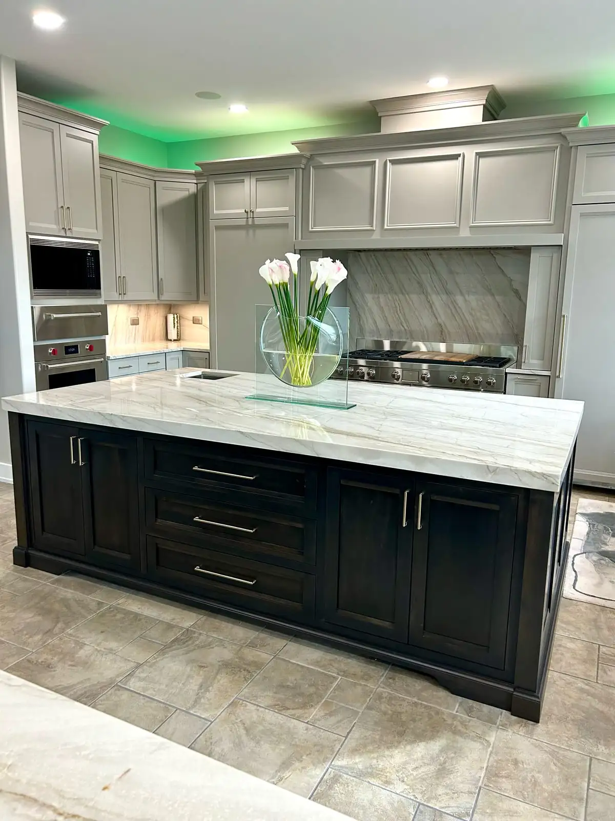 Grey kitchen with a dark island and a quartzite slab backsplash on the range wall