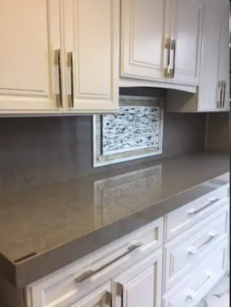 Light stone countertop with a glass mosaic accent panel in the backsplash