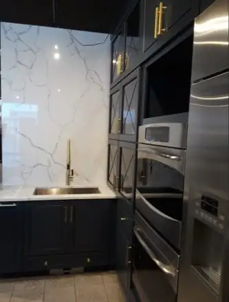 Veined quartz slab backsplash and countertop with a gold faucet over a dark base cabinet