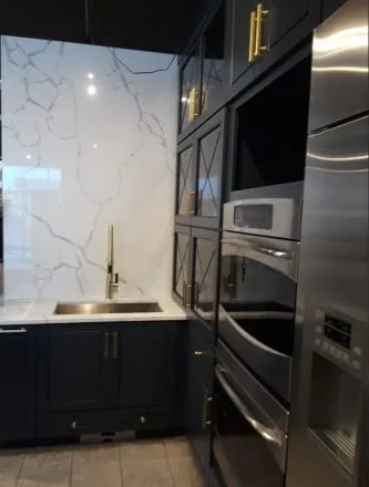 Veined quartz slab backsplash and countertop with a gold faucet over a dark base cabinet