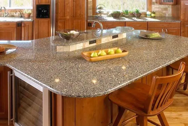 Speckled beige granite breakfast bar with a raised eating ledge and oak cabinetry