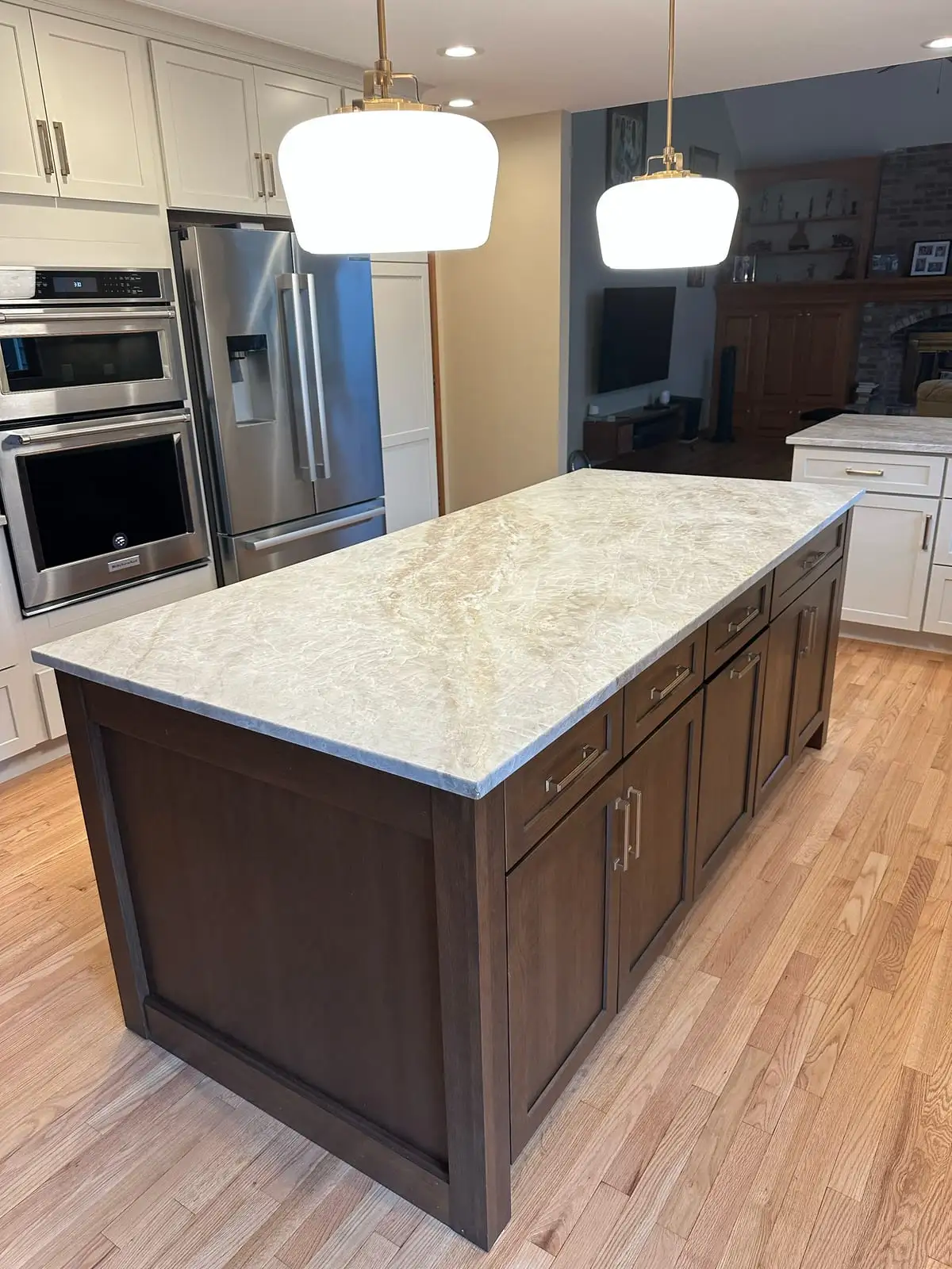 Taj Mahal quartzite island on a warm wood base with schoolhouse pendants