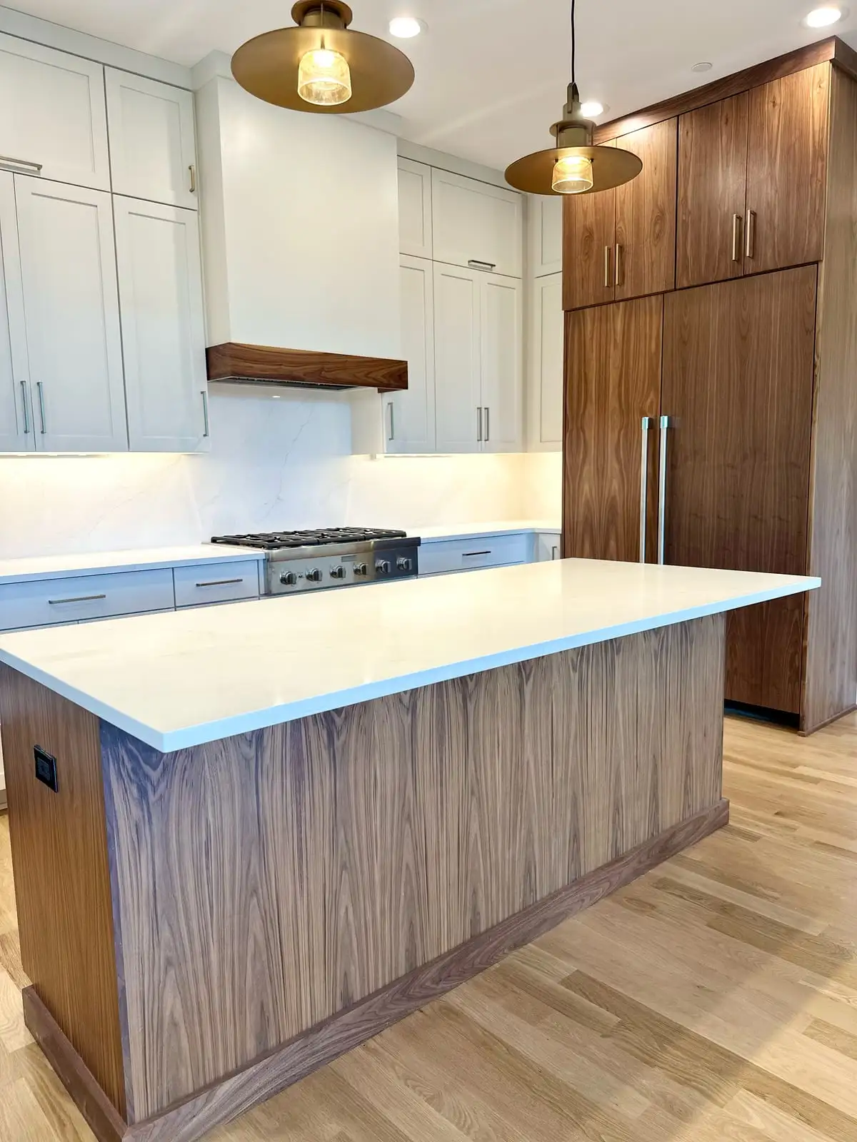 White quartz island top on a walnut base in a modern white-and-wood kitchen