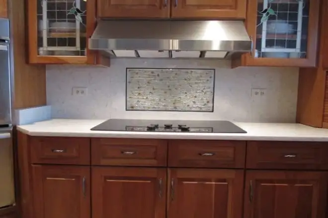 Cherry cabinets with white stone countertops and a downdraft cooktop