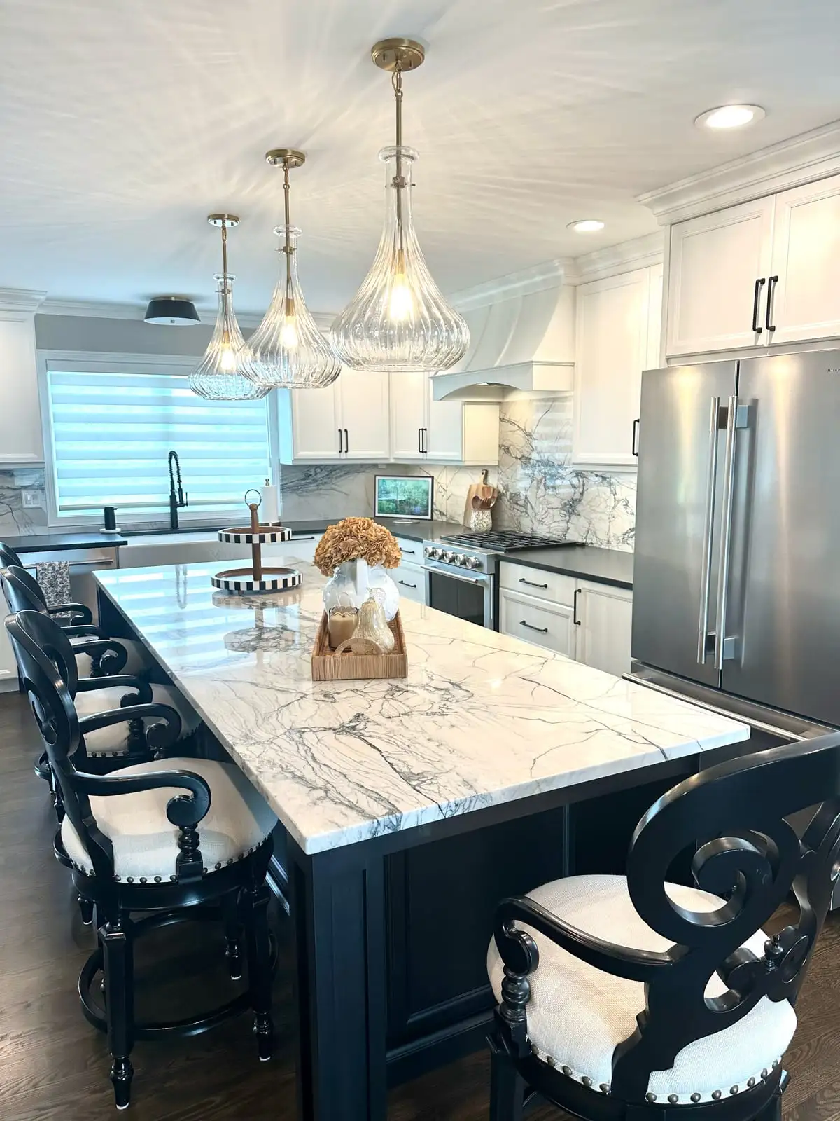 Long white marbled quartzite island with seating beneath three crystal pendants
