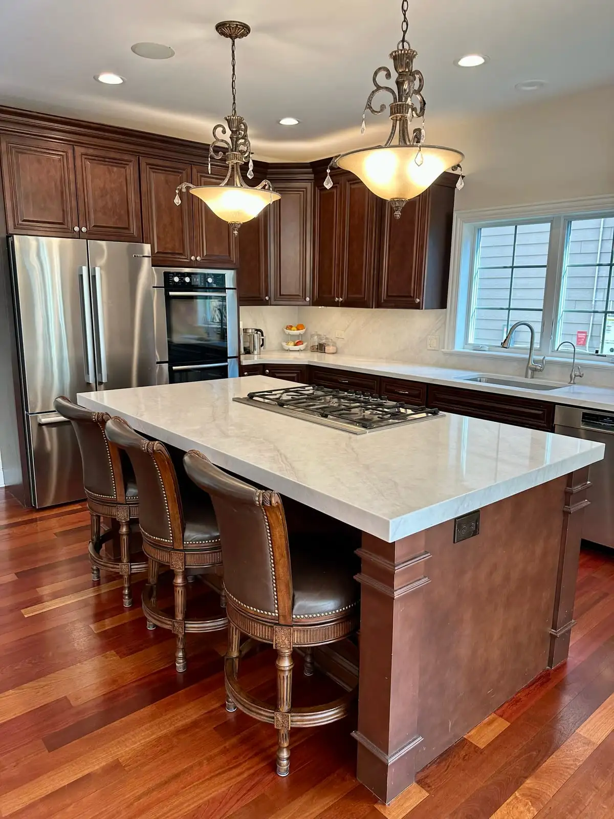 White quartzite island with a built-in cooktop in a traditional cherry-cabinet kitchen