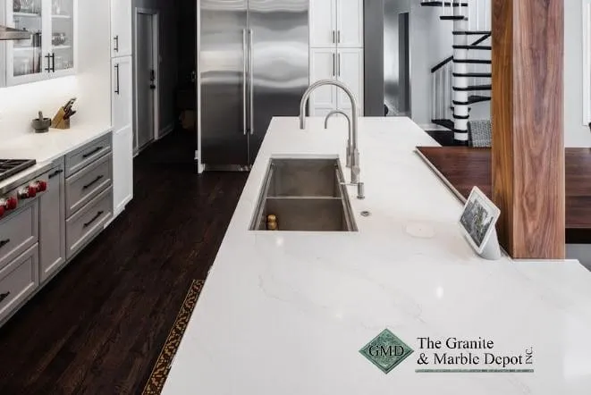 White quartz waterfall island with an integrated sink in a dark-cabinet kitchen