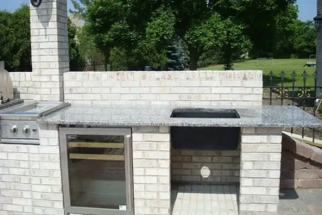 Outdoor kitchen with black stone counters over a cut stone base