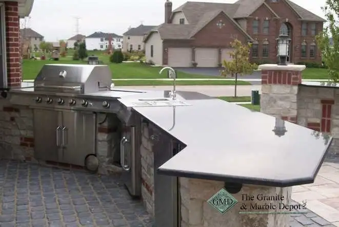 Outdoor kitchen island with a built-in grill and grey stone countertops