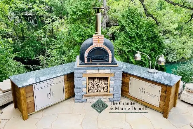 Outdoor pizza oven flanked by stone counters and cabinets