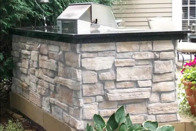 Cut stone outdoor kitchen counter topped with dark granite